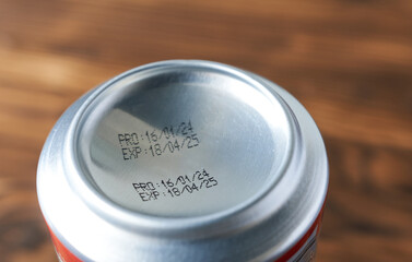 An aluminum beer can on a wooden background, close-up. Expiration date on a beer can.