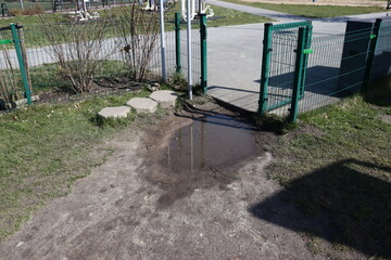 A puddle at the gate. A puddle makes it difficult to get to the playground