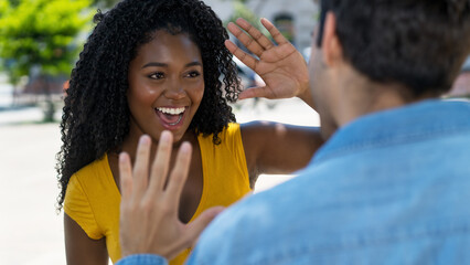 Happy black female young adult giving high five to latin american friend