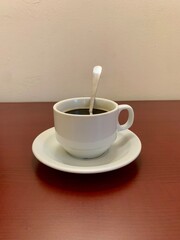 White cup of black coffee on the brown table