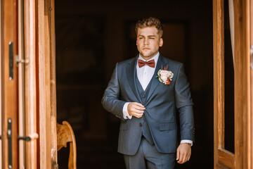Valmiera, Latvia - August 19, 2023 - Groom in a blue suit stands confidently in a doorway,...