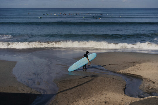 Surfer with a longboard on the beach near the ocean.