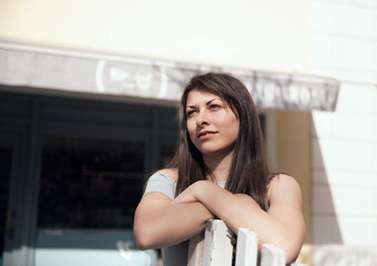 Young Woman Reflecting with Arms Crossed in Front of a Cafe