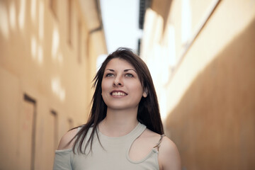 Optimistic Young Woman Looking Up in a Narrow Alleyway