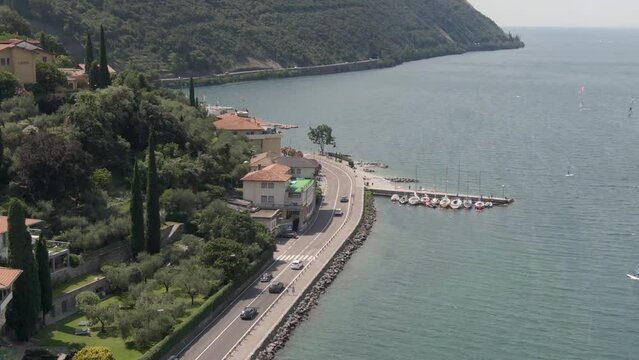 Aerial view of lake promenade on Lake Garda with cars on the road and windsurfers on the lake on a sunny day