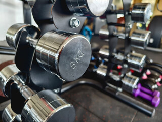 A rack of stainless steel or chrome coated dumbbells of various weights at a gym or fitness club.