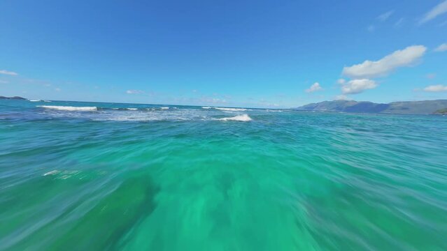 FPV speed flight over Caribbean Sea and green blue colors and foamy waves. Sunny day with clear water in Dominican Republic. Low angle flight.
