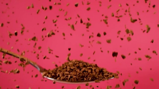 Nescafe grains drip onto a metal spoon in a close-up shot against a red backdrop, captured in slow-motion, symbolizing the concept of indulgence and sensory delight.