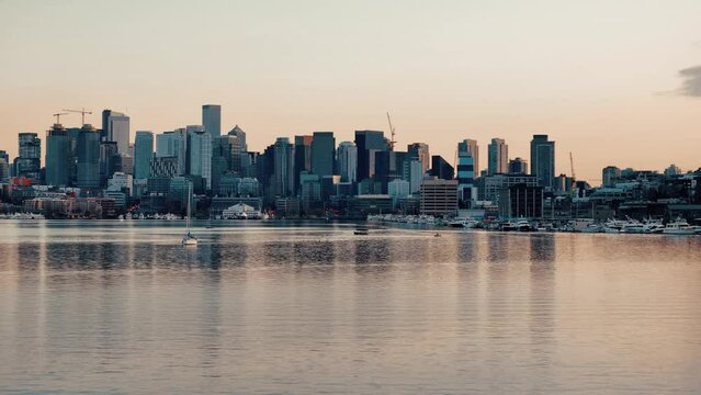 A single sailboat rests on the reflective water in Lake Union at dusk in front of the Seattle skyline and Space Needle