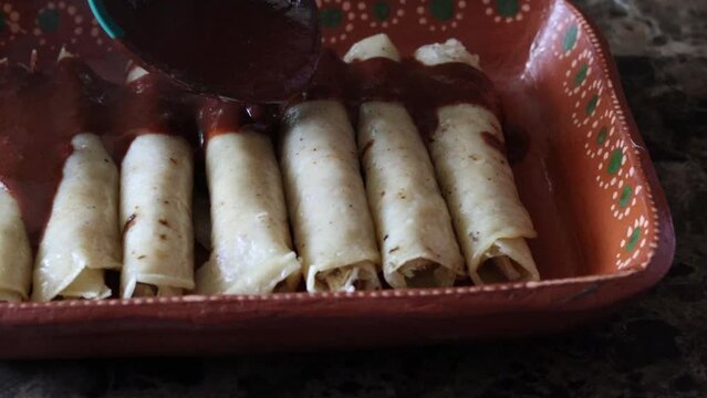 slow motion slider of person pouring black mole on chicken tacos, enchiladas enmoladas