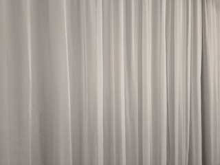 the curtain hangs from the ceiling to the floor. smooth satin synthetic curtain dividing the space and forming a soft textile background. weights at the bottom of the edge of the fabric