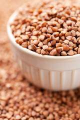 Uncooked, brown buckwheat grains in bowl. Dry buckwheat grains. Healthy food