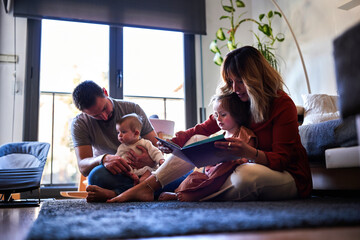 Family reading a book in the living room.