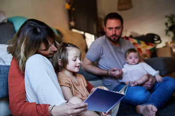 Young family reading storybook together in the living room floor.