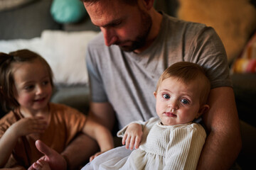 Obraz premium A baby in the arms of her father with her sibling looking her