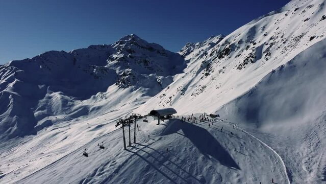 Chair lift station high in Alps during winter sport season, aerial