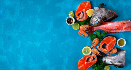 Fresh seafood assortment on blue background with copy space. Trout steaks, beaked redfish and...