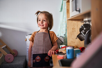 Happy little girl playing with child's kitchen.