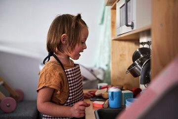 little girl playing with child's kitchen.