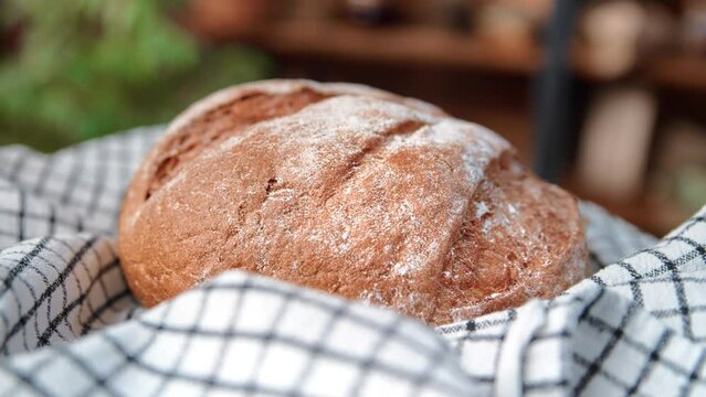 Homemade rye loaf on natural linen towel in home kitchen, closeup view, fresh bread spinning around