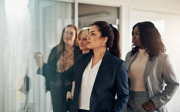 Team of diverse businesswomen brainstorming on an office whiteboard