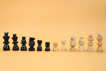 A row of wooden black and white chess pieces isolated on yellow background