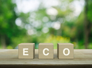 Eco letter on wood block cubes on wooden table over blur green tree in park, Business ecological...
