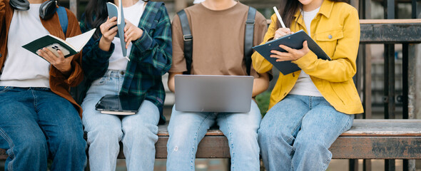 Young people college students is reading a book while relaxing sitting on grass in a campus park