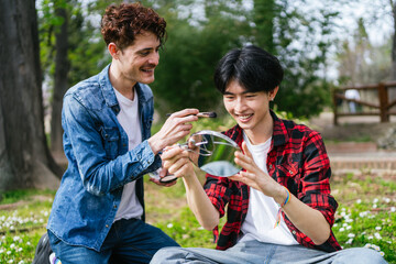 An LGBT couple, including a Chinese man, shares smiles and makeup tips in a park.