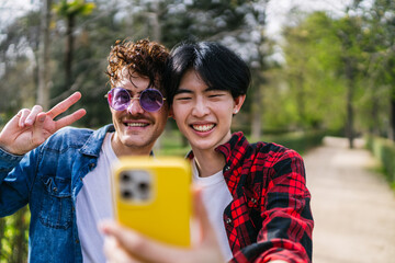 An intimate moment between a Chinese and Latino gay couple as they take a smiling selfie