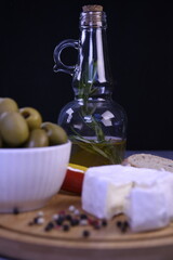 A quick healthy snack. Bread with hermelin cheese, camembert, olives and fresh peppers on a round wooden board.
