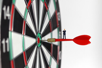 Business marketing success concept. A miniature businessman standing on a red arrow in the middle...