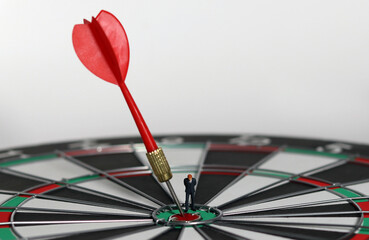 Fototapeta premium The red dart arrow in the middle of the dart paper is the goal of the business. An entrepreneur looking at arrows on a dartboard. Concept of business marketing plans and objectives. 