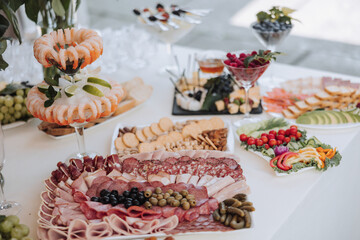 A table is covered with a variety of appetizers and snacks, including crackers, cheese, and fruit....