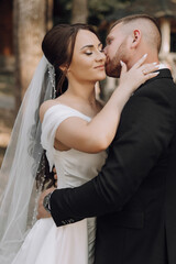 A bride and groom are kissing each other's lips. The bride is wearing a white dress and the groom is wearing a black suit