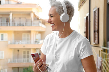 Middle Aged Woman With Short Haircut Listening To Music With Her Smartphone. Audiobook or Podcast...