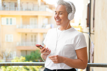 Middle Aged Woman With Short Haircut Listening To Music With Her Smartphone. Audiobook or Podcast...