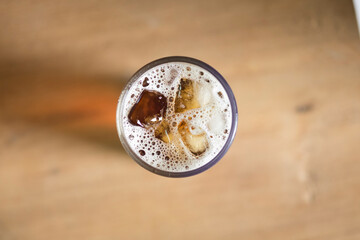Americano ice coffee in a glass, isolated on brown wooden table, with clipping path, top view, flat lay.