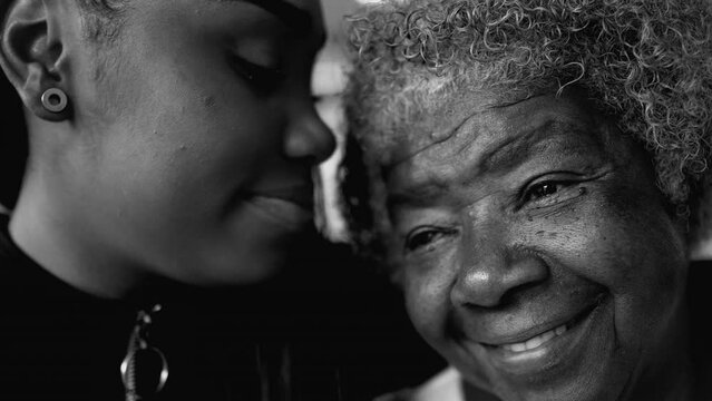 Affectionate Inter-generational Loving Moment Between African American Grandmother and Granddaughter, teen girl kissing her grandma in the forehead captured in black and white
