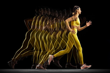 Athletic young woman in yellow sportswear captured in motion, training, running against black...