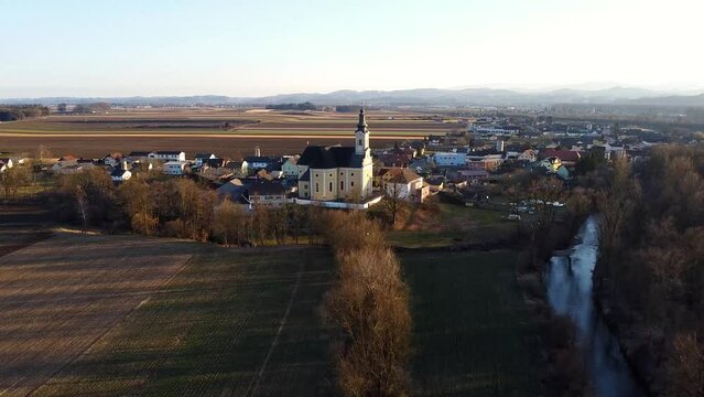 Aerial push toward Church in small European farming town at sunset.