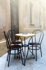 Tables of a cafe on the old city on soft sunlight