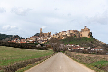 Panoramic view of the touristy medieval village Frías built on a mountain in front of a large field in Burgos.