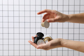 Coffee capsules with foil in hand on light background