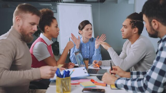 Diverse professionals engaged in heated debate during office meeting, dynamic interaction and strategic discussion. Passion and involvement of team members, ideas and viewpoints exchanged