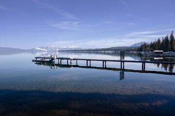 Pier, mountains with snow on calm Lake Tahoe, Homewood, California, United States of America.