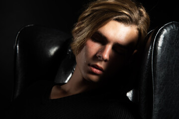 A young attractive guy is resting. Black background.