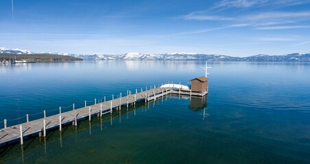 Pier, mountains with snow on calm Lake Tahoe, , Tahoe City, California, United States of America.