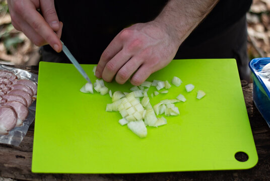 Cutting red paprika on a green cutting board in the forest