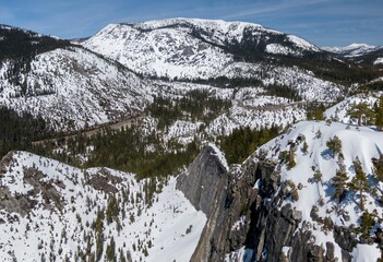 Aerial: Snow covered Mountains and forest in the sierra Nevada ranges Twin Bridges, California,...